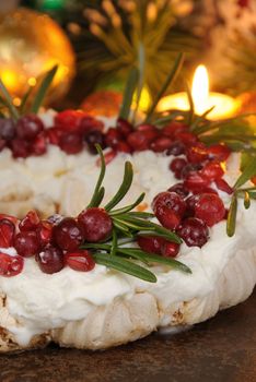 Christmas wreath made of meringue with cream, pomegranate, cranberry, rosemary closeup