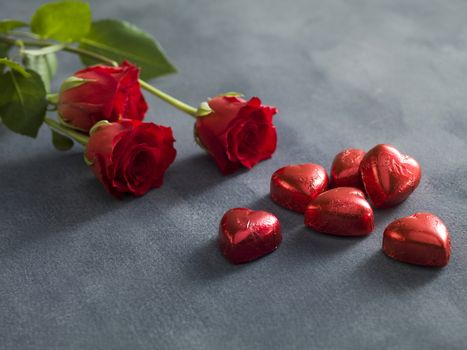 Bouquet of red roses and hart shaped chocolates. A valentines day concept