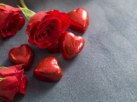 Chocolate hearts and red roses on a grey background. Valentines day background
