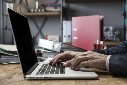 Close up of a middle age businessman working on his laptop at home at his dinner table