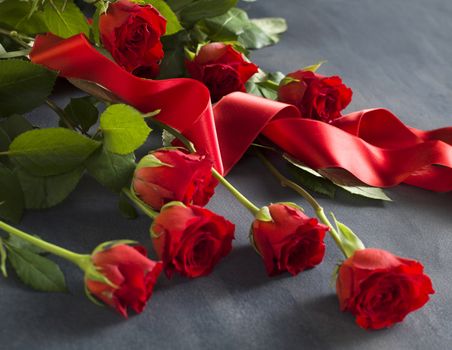 Grey stone with a bunch of red roses and a red ribbon