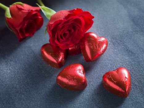 Red roses and chocolate hearts on a dark blue background. Valentines day background