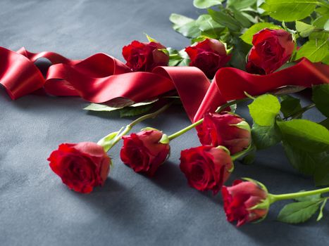 Red roses and ribbon on grey a board. Valentines Day background.