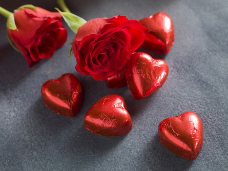 Red roses with chocolate hearts on a dark blue background. Valentines day background