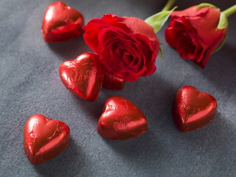 Red roses with chocolate hearts on a grey background. Valentines day background