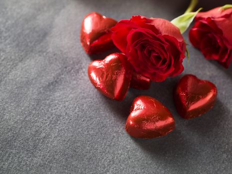 Red roses with chocolate hearts on a grey background. weddings day background