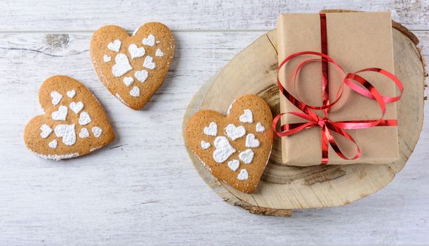 Box with a present to the Valentine's Day and cookies in the shape of heart lie on the white table