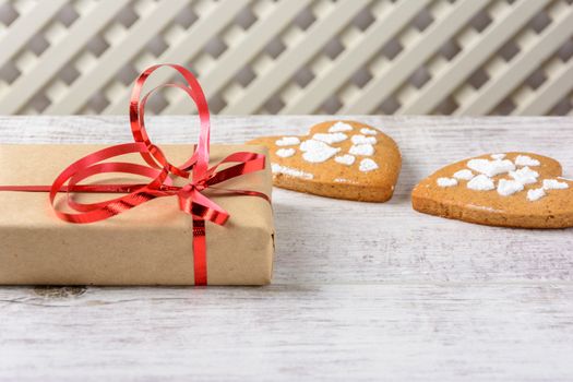 Box with a present to the Valentine's Day and cookies in the shape of heart lie on the white table