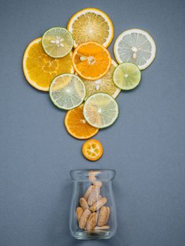 Healthy foods and medicine concept. Bottle of vitamin C and various citrus fruits. Citrus fruits sliced lime,orange and lemon on gray background flat lay.