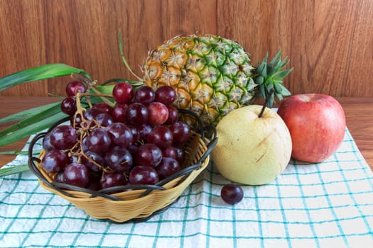 Still life with fruits in the basket on the wooden board.