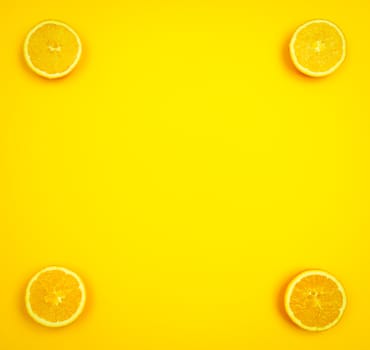 Orange slices in the corners of a yellowish background with copy space