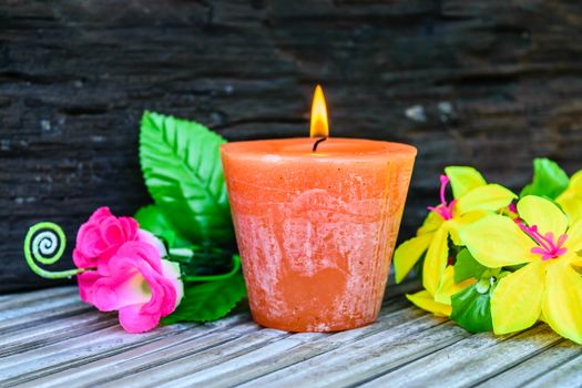 candles and flowers plastic beautiful on bamboo table on old wood background