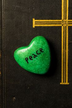 Catholic religion and peace concept represented by an old bible cover and a green - hope - heart.