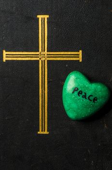 Catholic religion and peace concept represented by an old bible cover and a green - hope - heart.