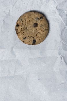 Macro shot of a danish cookie with chocolate drops over a white recycled paper background.