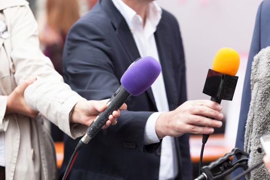 Journalists holding microphones, conducting press interview
