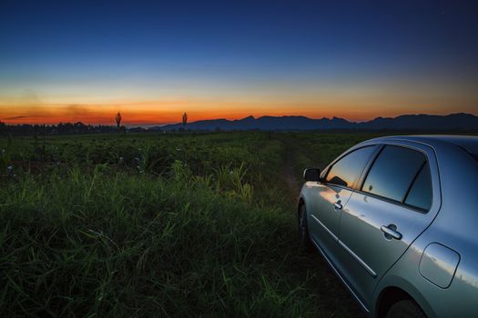 car on country road of agriculture field with beautiful sun set sky 