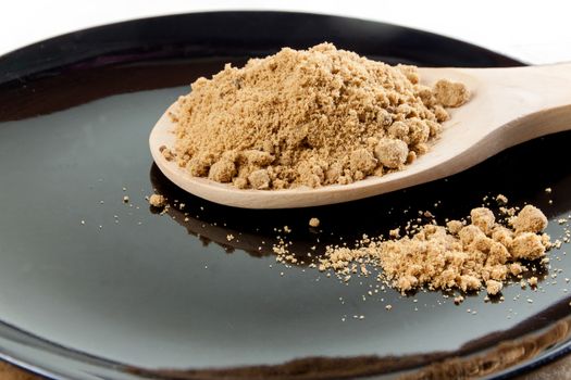 Brown cane sugar in a wooden spoon on the black background. Pure cane sugar for natural. no additives.