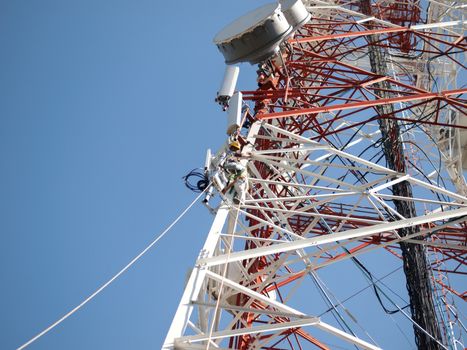 COLOR PHOTO OF TELECOM WORKERS REPAIRING CABLES ON TOWER