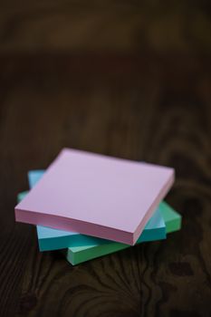 Stack of different colored notepads on ditressed wood background, shallow DOF