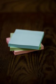 Stack of different colored notepads on ditressed wood background, shallow DOF