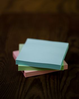 Stack of different colored notepads on ditressed wood background, shallow DOF