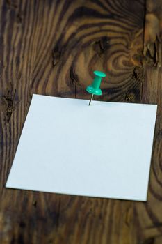 Green thumbtack pins note to distressed wood, shallow DOF