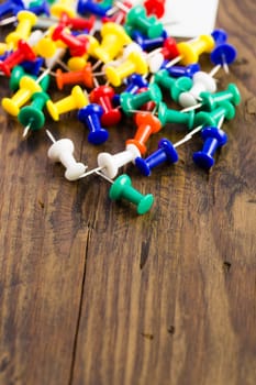 Thumbtack pins note to distressed wood surrounded by colored tacks