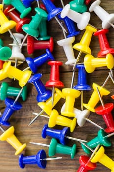 Pile of various color thumbtacks  on distressed wood