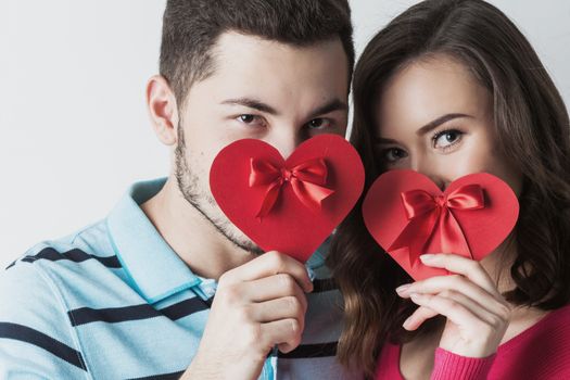 Young couple celebrating Valentine day holding paper heart cards