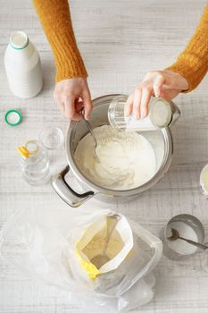 Woman makes the dough in the pan on the white table vertical