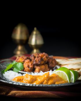 Indian dinner consisting of chicken korma, rice, pakoras and nan bread.