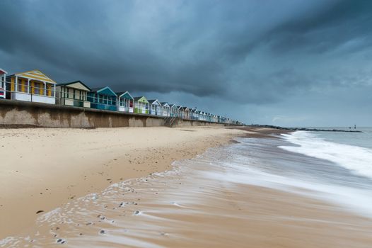 A row of beach huts next to Southwold Pier at sunrise