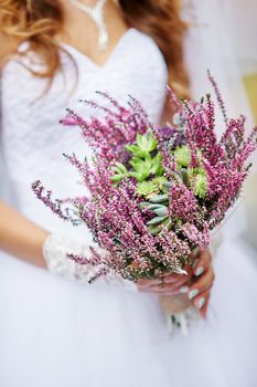 bride holding a beautiful wedding bouquet of wild flowers.