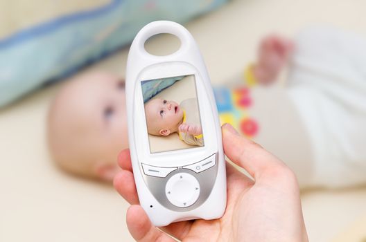 Hand holding video baby monitor for security of the baby