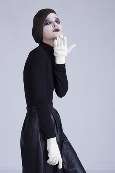 Young woman mime on a background of gray wall