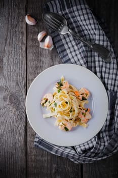 Tagliatelle with shrimps on the pan placed on a wooden surface