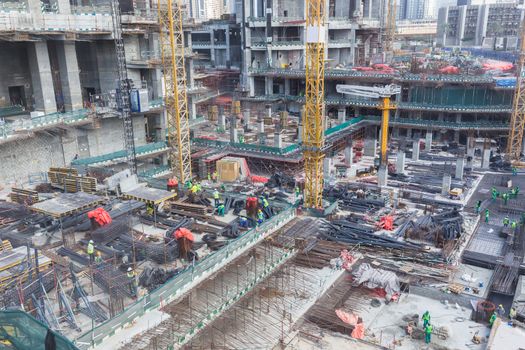 Laborers working on modern constraction site works in Dubai. Fast urban development consept.