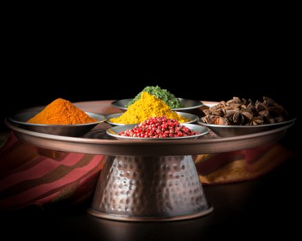 Colorful variety of spices on a copper presentation platter.