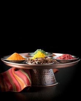 Colorful array of five spices on a copper presentation platter.