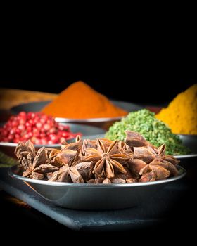 Closeup photograph of star of anise with other colorful spices in the background.