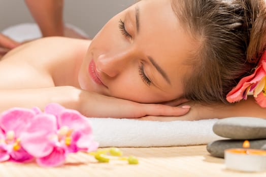 brunette with closed eyes relaxes during a back massage at the spa