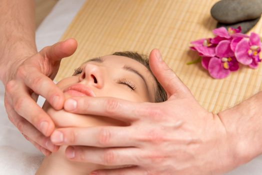 male hands of the masseur, cosmetologist, doing massage the girl face