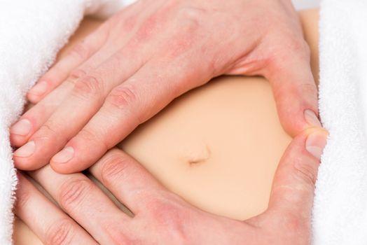 male hands in a heart shape on the abdomen of a pregnant woman close-up