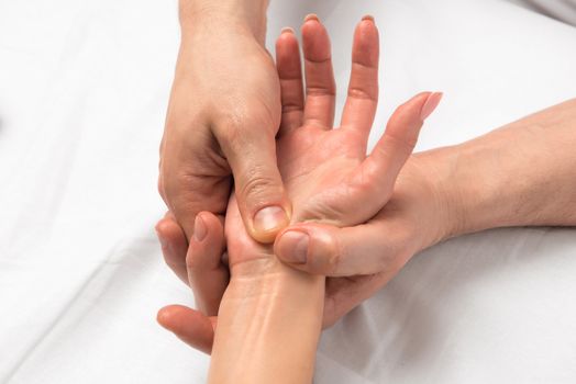 Photo of reception massage hands closeup on white sheets