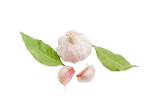 One garlic bulb and two garlic cloves, two dried bay leaves on a light background closeup
