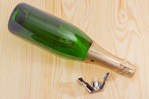 Bottle sparkling wine and special stopper for wine storage on a light wooden surface closeup
