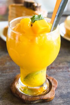 mango smoothie in glass on wooden table