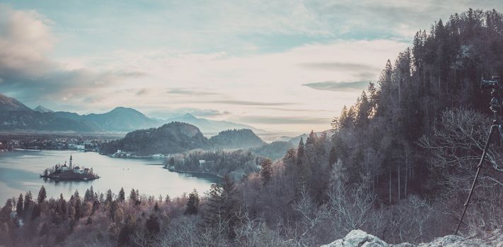 Winter panorama at sunrise  with the Bled lake and village, surrounded by the Julian Alps and a camera mounted on a tripod