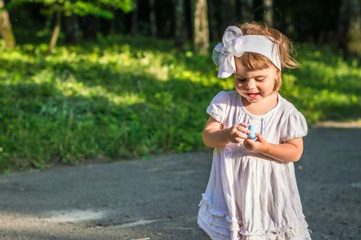 a little girl draws on asphalt in the Park in summer